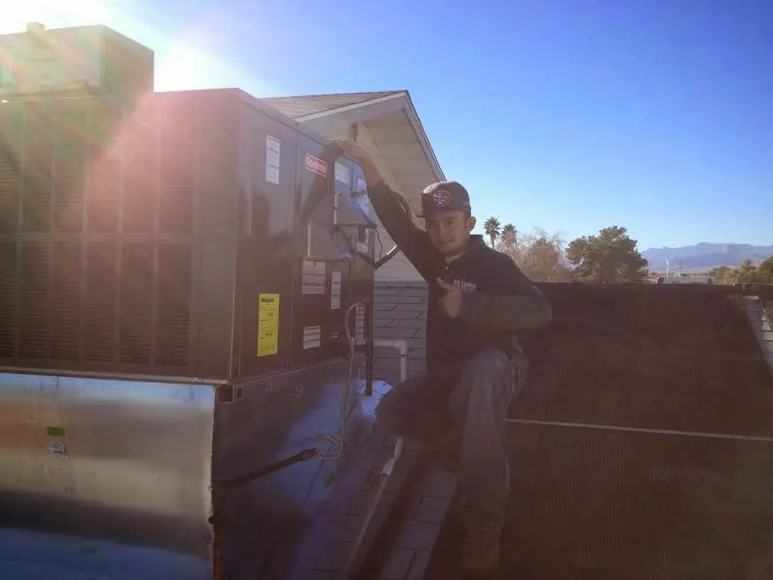 HVAC technician performing AC Tune-Up on a rooftop unit in Foley